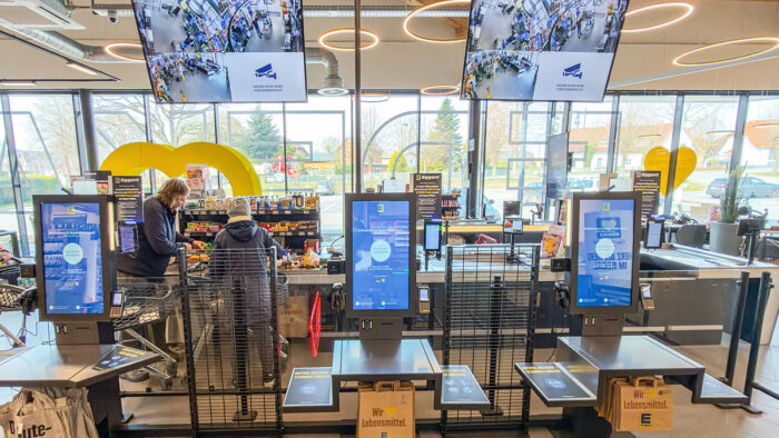 Deckenmontierte Monitore über der SCO-Zone zeigen die Videoüberwachung des Bereichs in Echtzeit