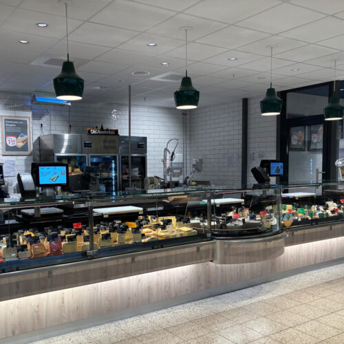 Holzverkleidung und dunkelgrüne Pendelleuchten prägen das Erscheinungsbild.