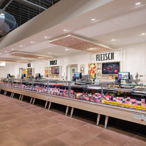 Die Bedientheke mit hellem Holzunterbau fügt sich optisch in das Storedesign ein