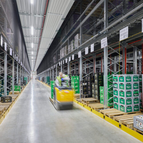 Auf Fahrwegen zwischen den Palettenregalen werden Bierkisten zügig kommissioniert