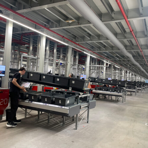 Mitarbeitende entnehmen Artikel aus Autostore-Behältern an den Pickstationen