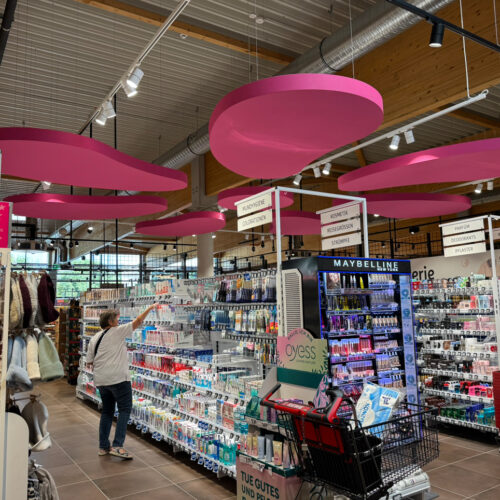 Die Drogerieabteilung hebt sich mit einem Deckensegel in Blütenform und beleuchteten Regalböden optisch ab
