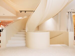 Eine historische Wendeltreppe bleibt ein zentrales Element des Modehauses und wurde in dem prägnanten Gelbton gefärbt, der den gesamten Store umgibt.