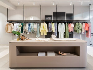 Deckenhängende Stangensysteme in Schwarz und ein zentraler Präsentationstisch kennzeichnen die Damen-Premium-Abteilung