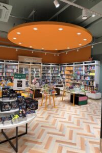 Die separate Kinderbuchabteilung wird von einer markanten orangen Deckenleuchte akzentuiert.