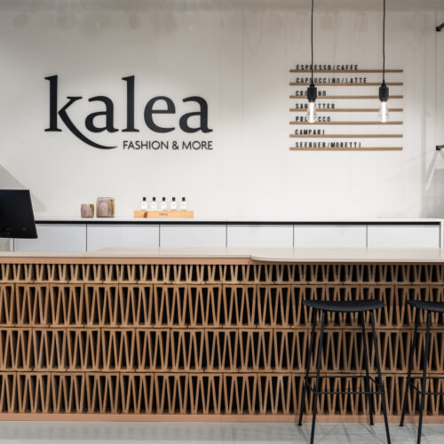 Die Kasse aus dreidimensionalen Ziegelsteinen dient gleichzeitig als Cafébar – mit Barhockern und Getränkekarte an der Wand