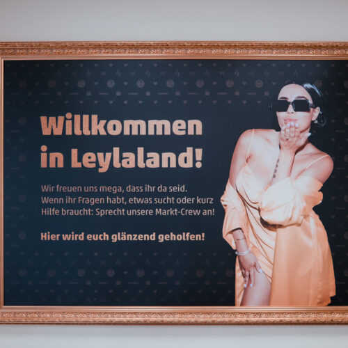 Ein gerahmtes Wandbild am Eingang begrüßt die Kund:innen