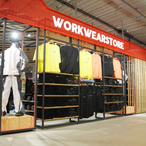 Ein rotes Streckmetall-Vordach mit dem Schriftzug „Workwearstore" markiert den Eingang des Shop-in-Shops