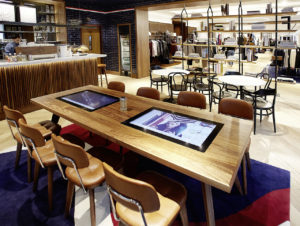 Der People‘s Place ist eine Community und Gastrofläche. Auch hier laufen Lifestyle-Videos auf Screens, die in die Tische eingelassen sind. (Foto: Tommy Hilfiger)