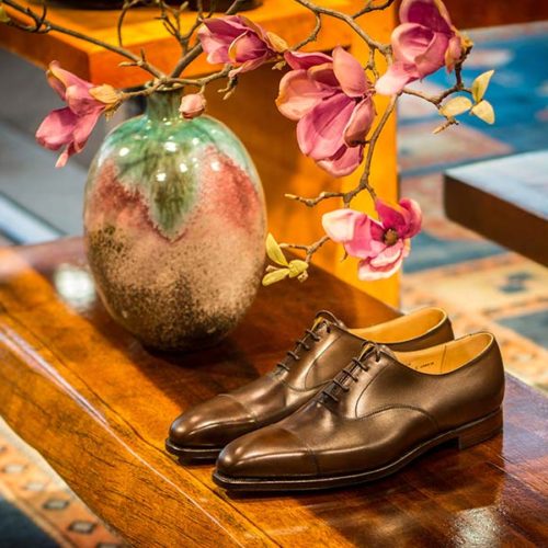 Ansonsten werden in diesem kleinen Store vor allem rahmengenähte, handgefertigten Herrenschuhe der britischen Marke Crockett and Jones verkauft, daneben Hemden, Regenschirme, maßgefertigte Gürtel, Schuhpflege-Artikel und Vintage-Manschettenknöpfe. Abgerundet werden Sortiment und Storedesign von der Fotokunst an den Wänden, die ebenfalls zum Verkauf stehen. Die Möbel und den Mustermix komplettierenden Teppiche stammen aus Vintage-Beständen. Das Interior-Konzept wurde komplett in Eigenregie entworfen und umgesetzt. (Foto: Marc Junghans Photography)