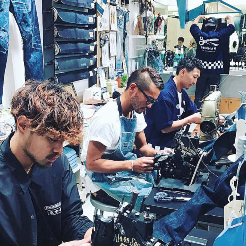 Das Denham Denim-Lab im Store Tokio Ginza: Coole Jungs customizen Jeans, im Schaufenster ein großer Waschtrog. (Foto: Denham The Jeanmaker)