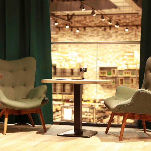 Eine Lounge mit grünen Sesseln lädt Kunden zum Verweilen auf der Empore ein. (Foto: Edeka Schmidt)